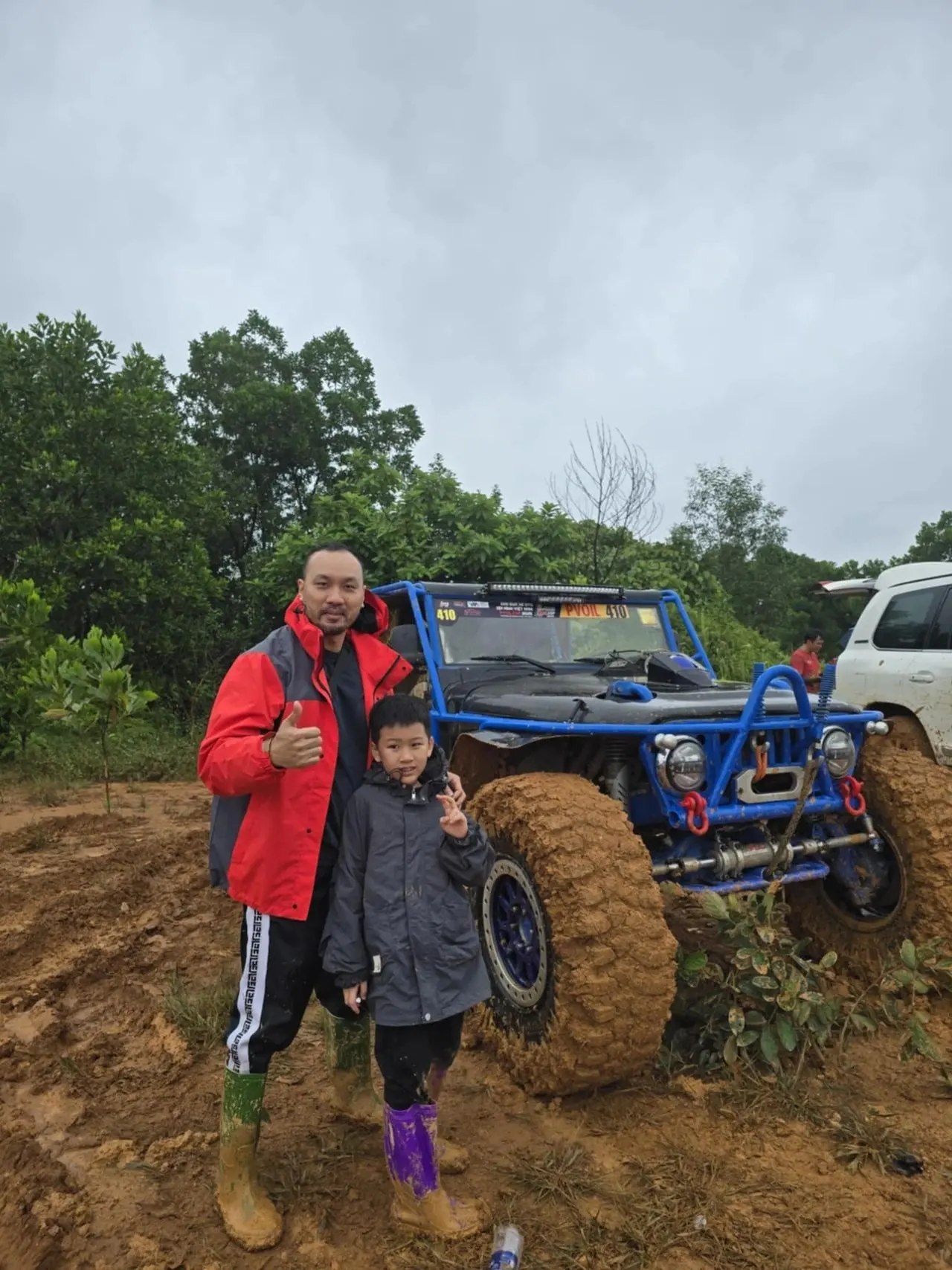 Tony và con trai tại giải off-road PVOIL, ủng lấm bùn, chiếc xe địa hình phía sau
